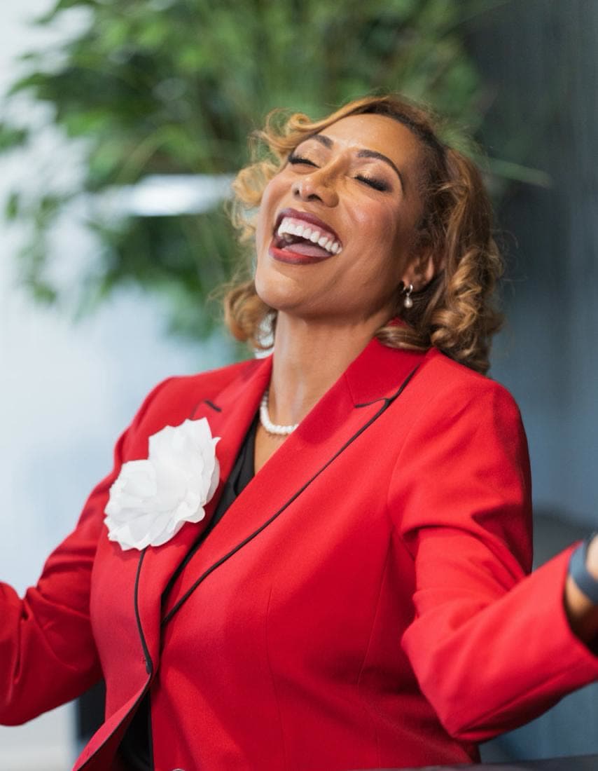 Dr. Stephanie laughing, in a red suit